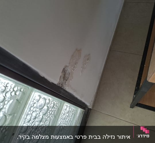 קיר עם סימני רטיבות ליד חלון זכוכית